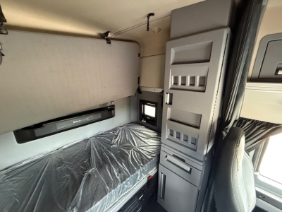 Truck cab interior showing upper bunk with plastic cover, storage compartments, and control panels in a Mack Anthem sleeper tractor.