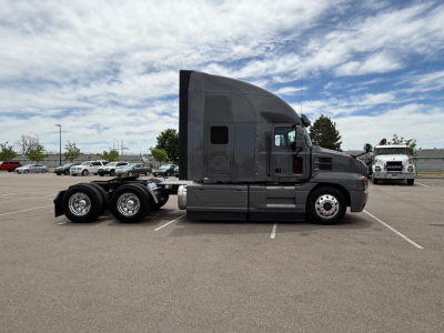 Mack ANTHEM semi truck side view with sleeper cab in dark gray, three rear axles, chrome wheels, and hooded engine bay.