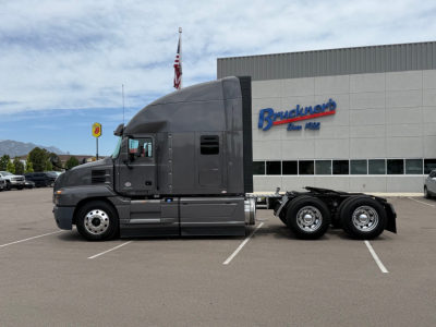 Truck cab and chassis of a 2024 Mack Anthem in a parking lot, side view showing sleeper cab and dual rear axles.