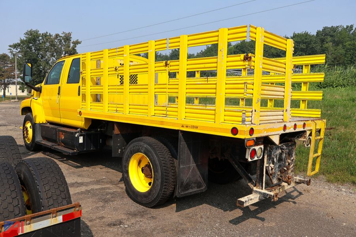 Chevrolet Kodiak C7500 crew cab stake truck with bright yellow stake bed and rear bumper area.