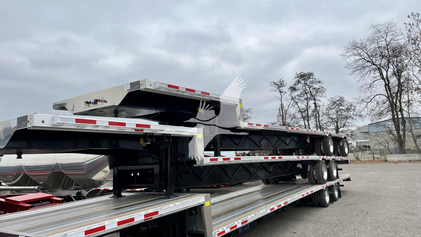 Transcraft combo drop trailer viewed from side showing dual deck and loading frames with chrome finish and reflective safety tape