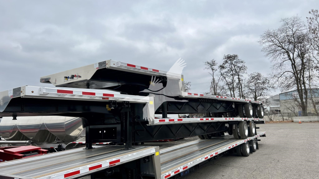 Transcraft combo drop trailer viewed from side showing dual deck and loading frames with chrome finish and reflective safety tape