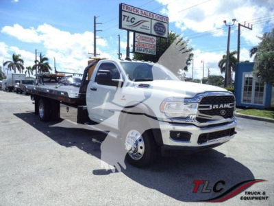 Ram 5500 rollback tow truck front left view showing chrome grille, dual rear wheels, extended flatbed, TLC Truck Sales Center sign in background.