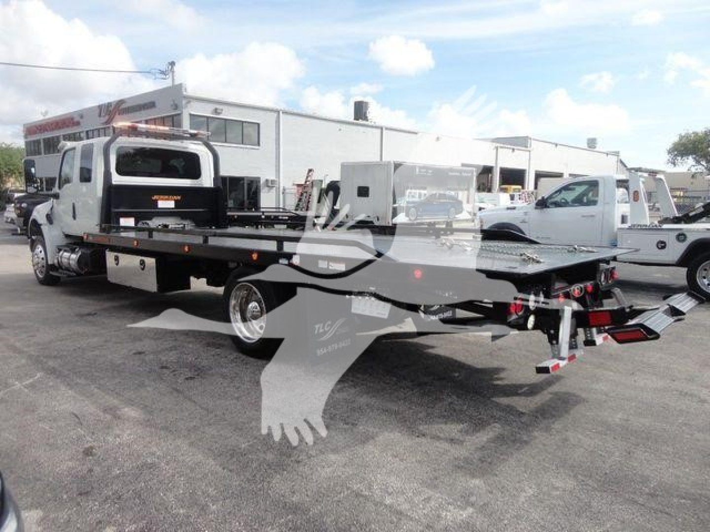 Truck flatbed tow bed at a dealership with MV607EXCAB22XLP stock number visible in the lot.