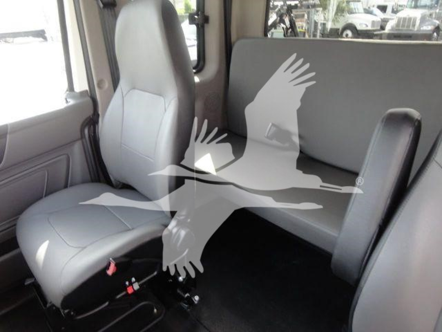 Cab interior of a new International MV rollover truck showing front seat and rear seating area with light gray upholstery