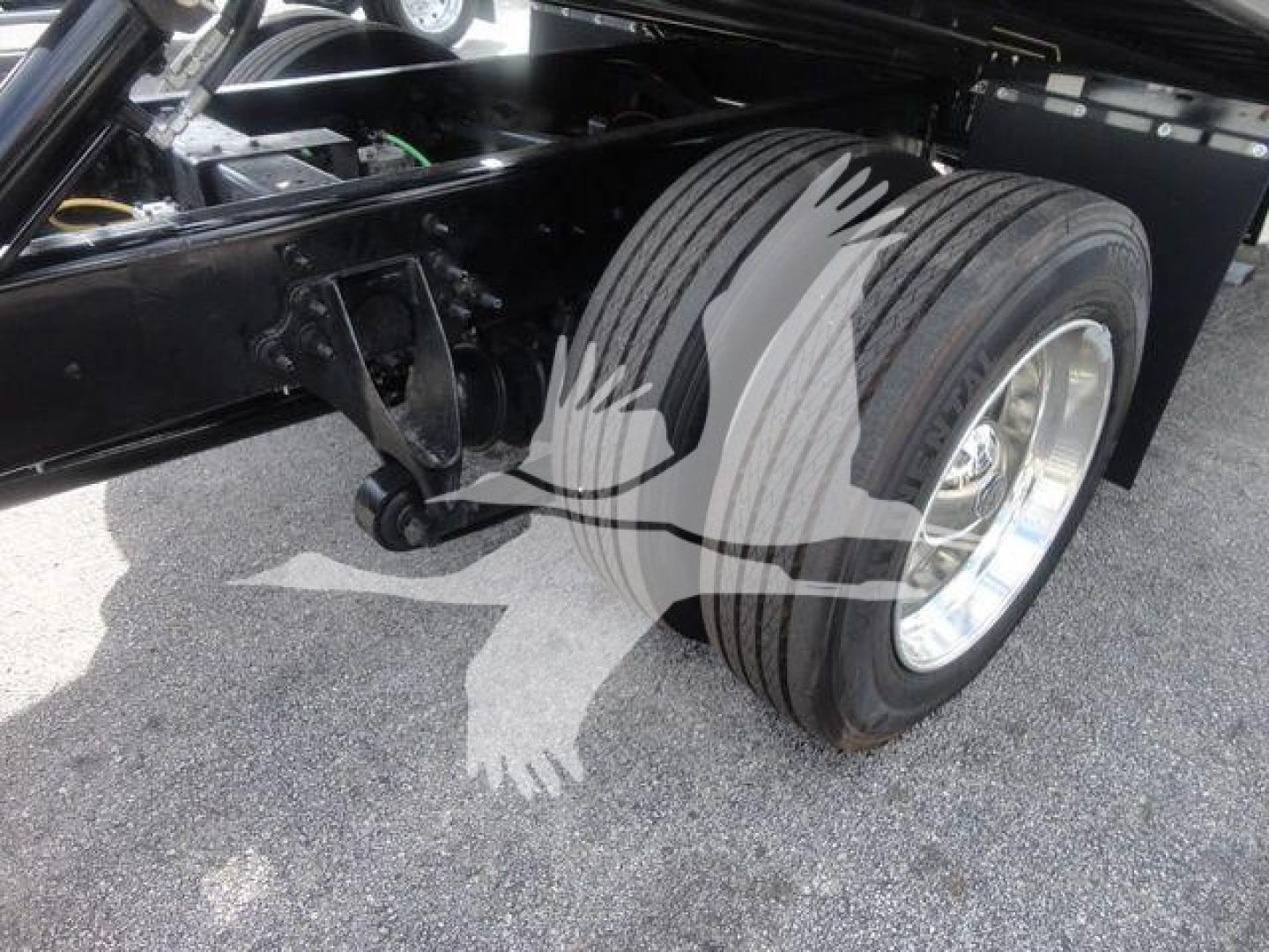 Truck front dual rear wheels on a component frame with leaf spring suspension and black chassis visible.