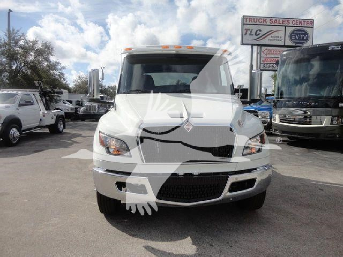 Truck front view of a 2027 International MV with white cab and grille, parked in a dealership lot.