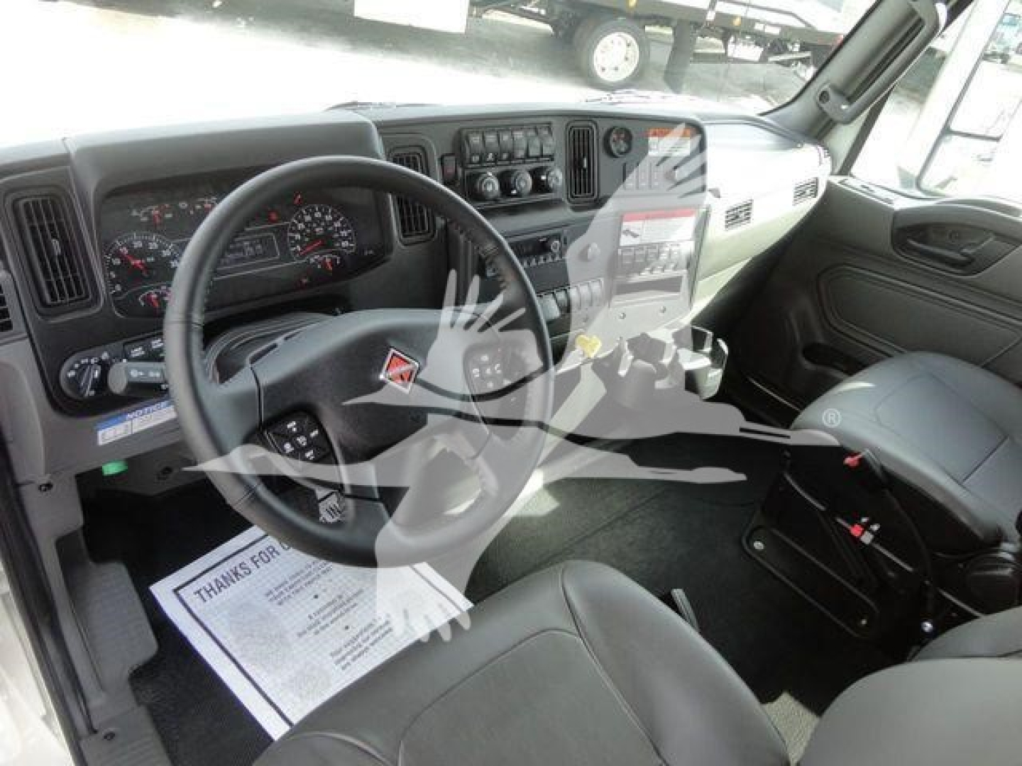 Interior view of a 2027 International MV truck cab showing steering wheel, dashboard, and front seats.