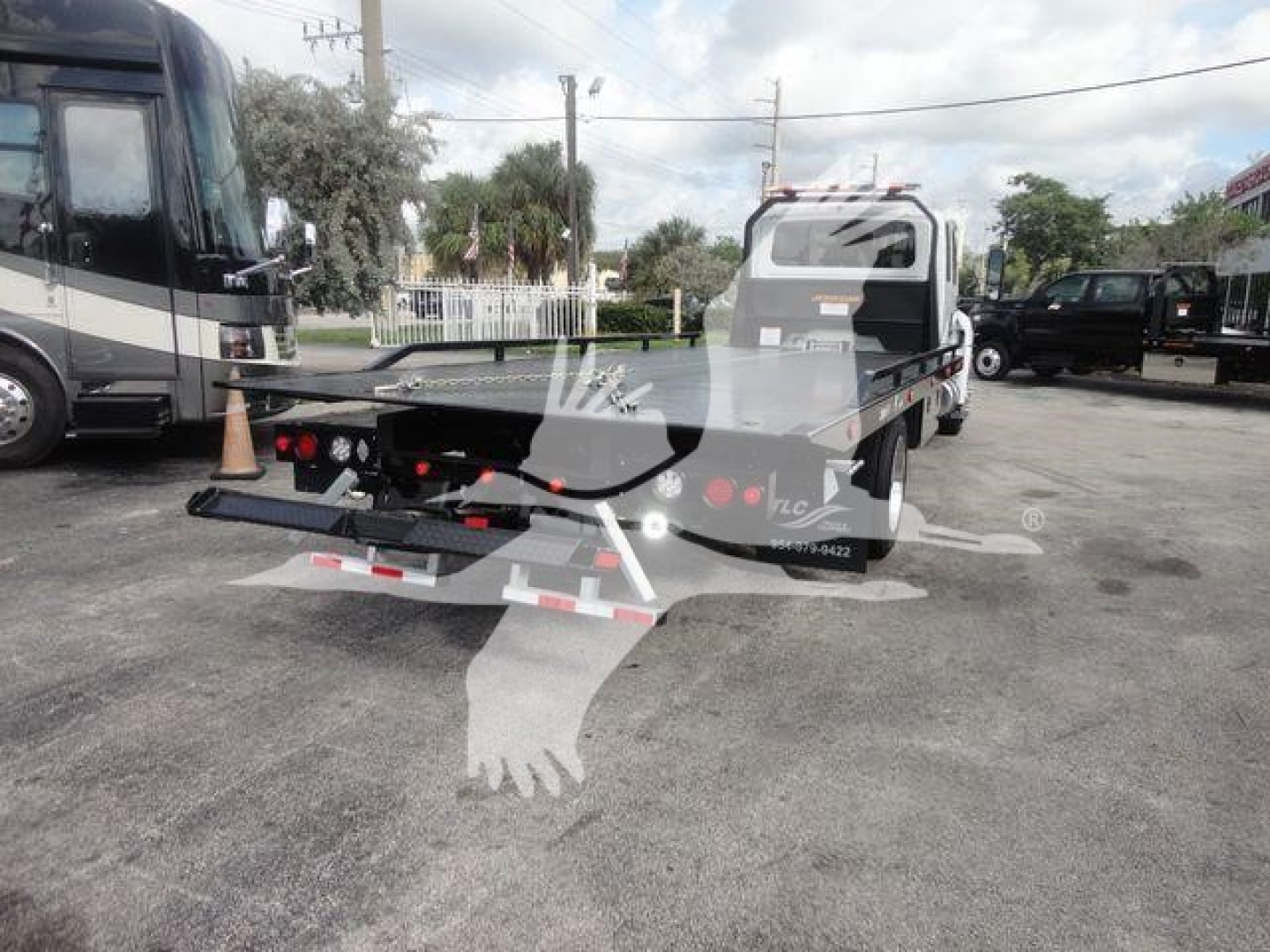 Vehicle rear view showing rollback tow truck bed and winch assembly with taillights and bumper.