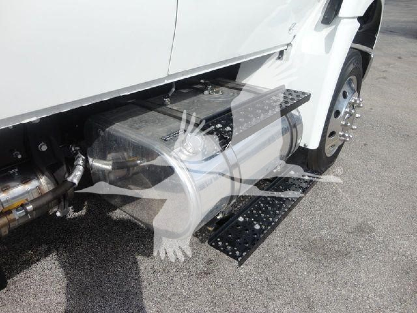 Truck side view showing metal step/step bracket and fuel tank area on International MV with white cab.