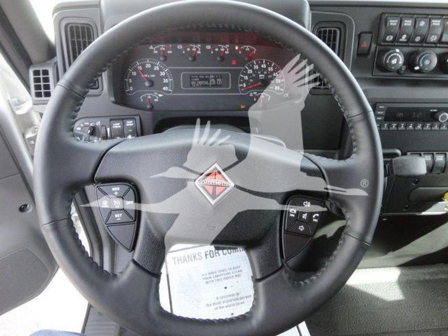 Truck steering wheel and dashboard of a 2027 International MV showing instrument cluster and steering controls.