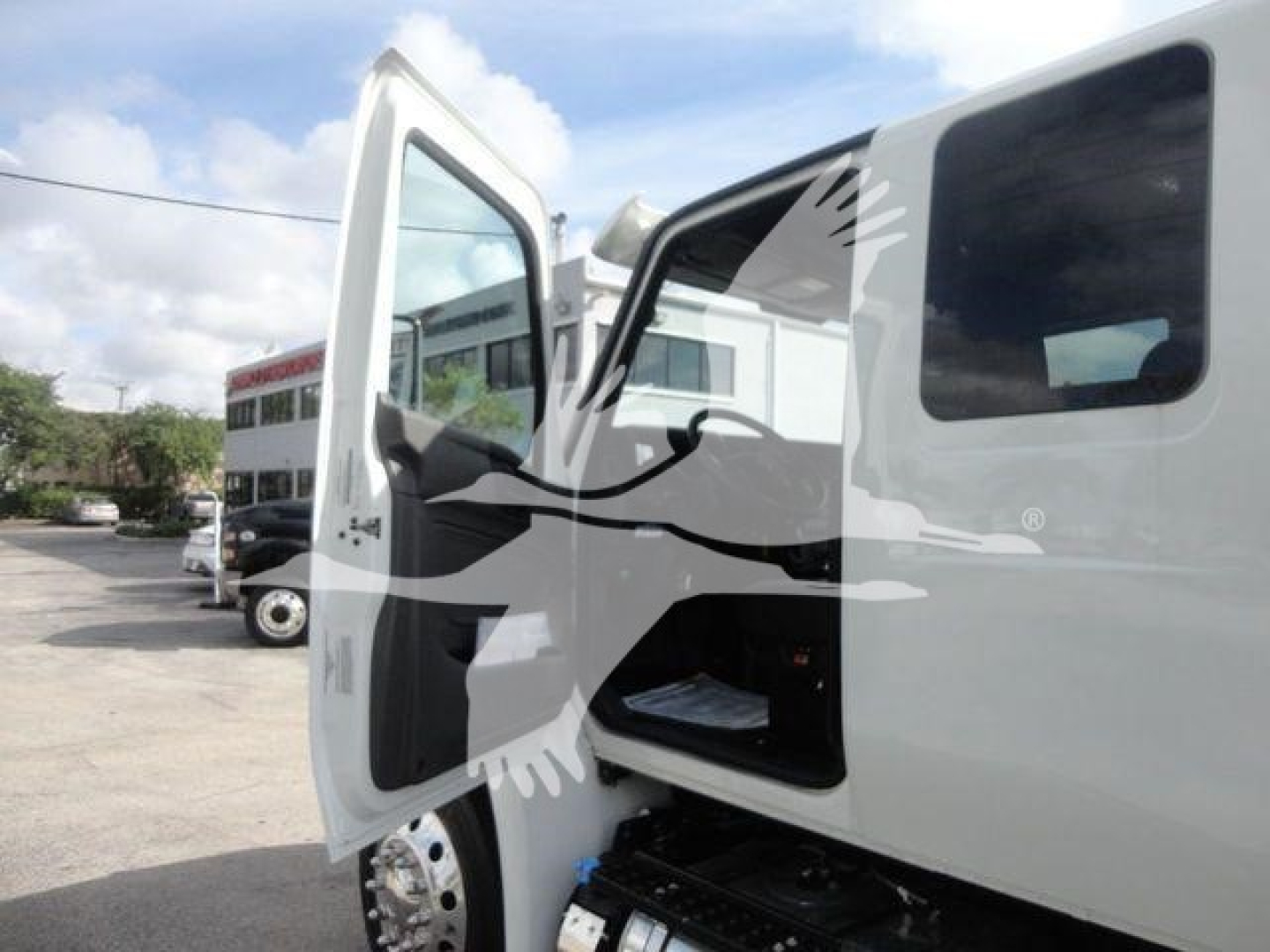 Truck cab with open door showing interior and storage, International MV series van-like truck side view.