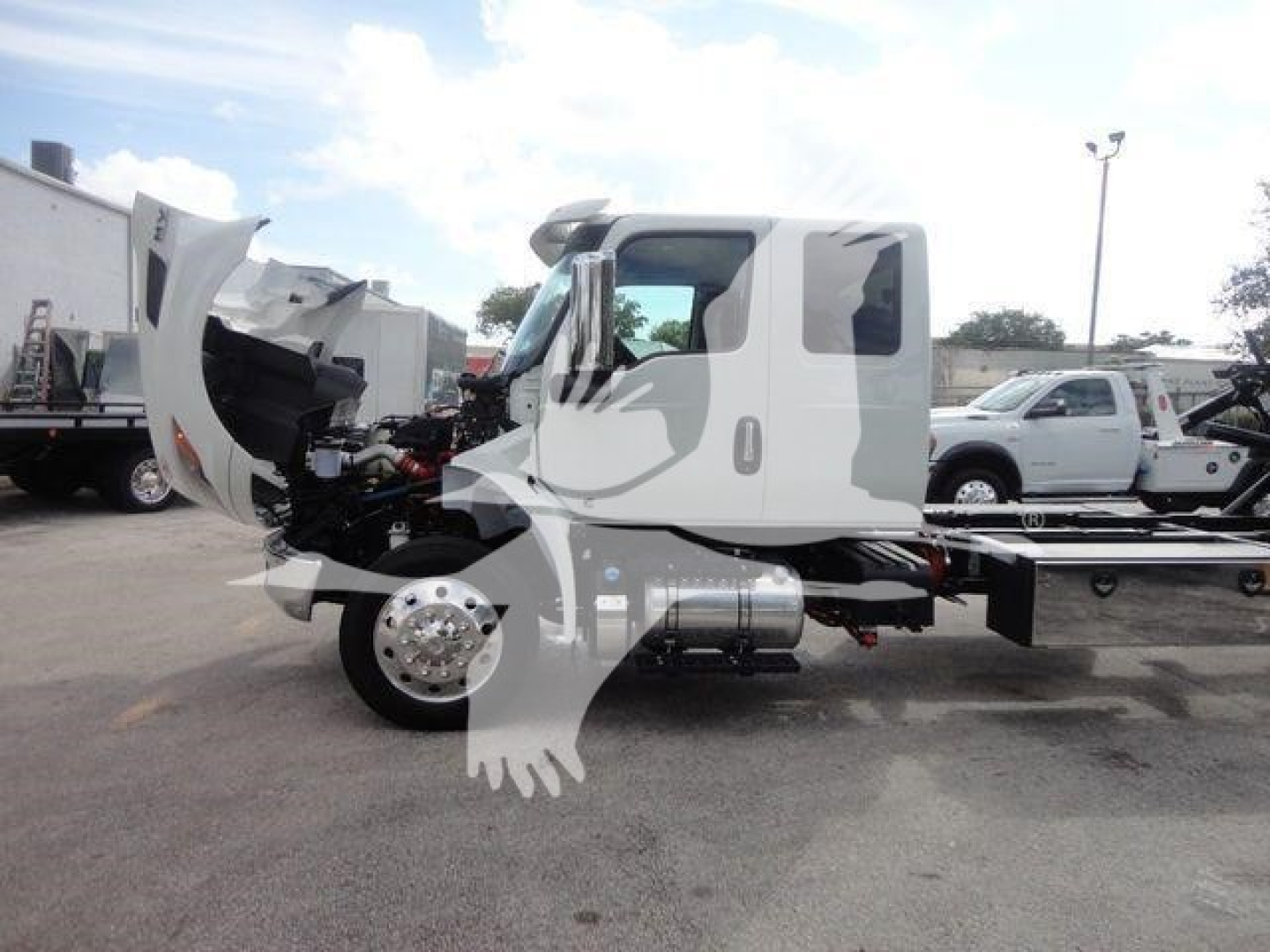 Truck cab and chassis of a new 2027 International MV rollback truck with hood open revealing engine compartment.