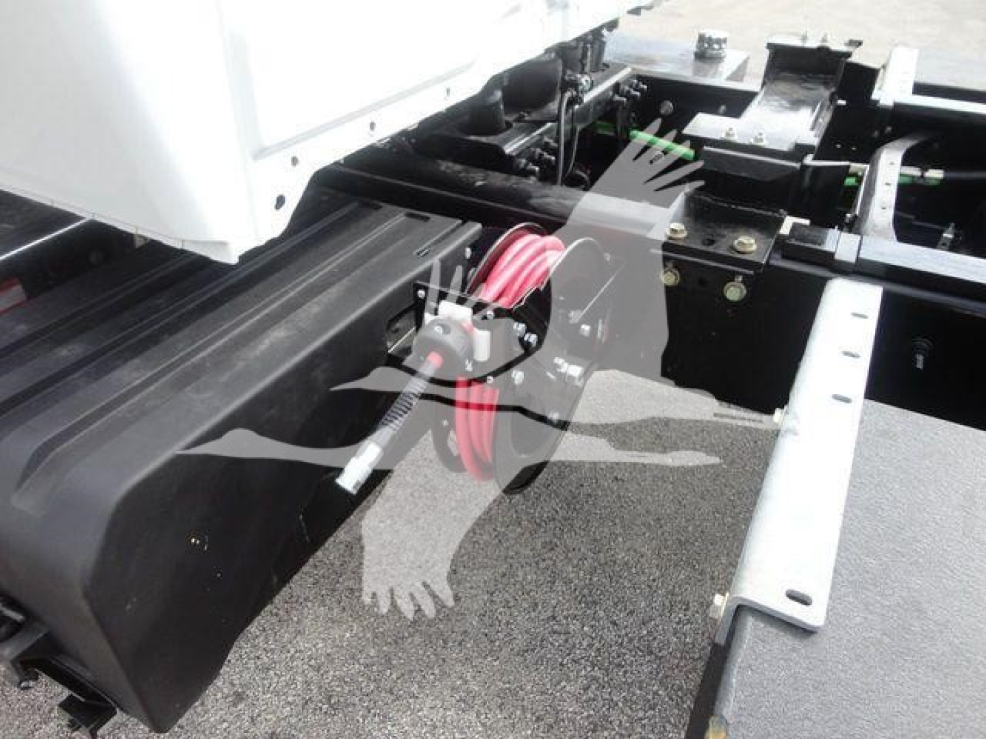 Truck chassis showing a black battery box with red power cables and connectors, exposed under a cab on a MV series International truck.