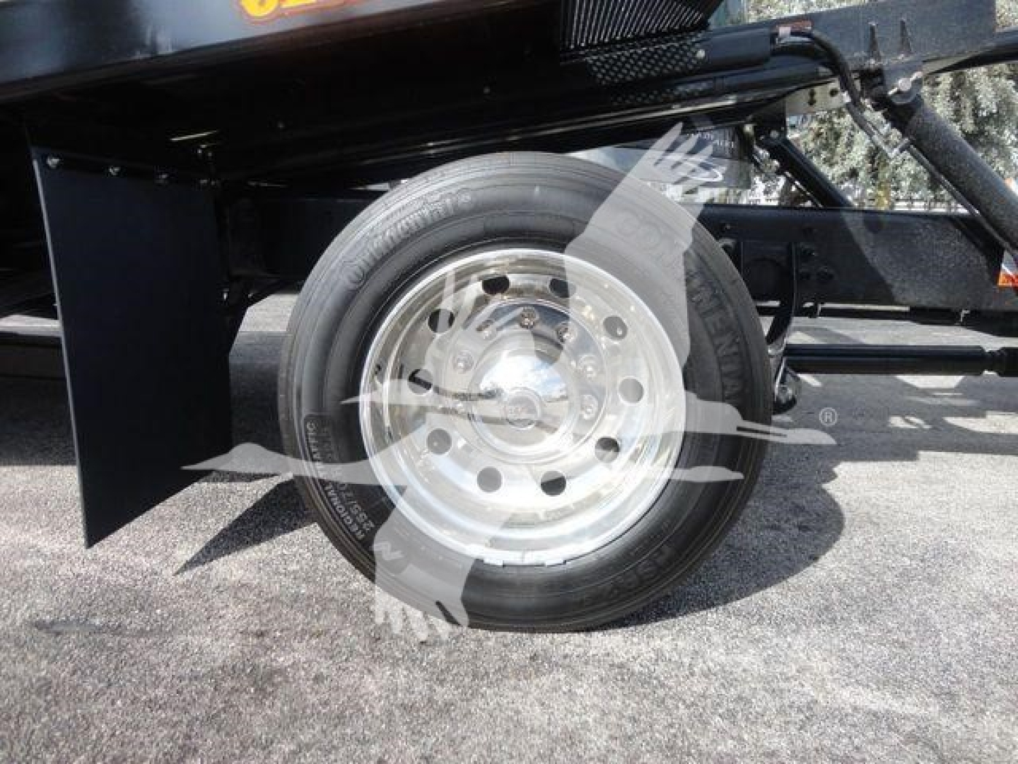 Truck wheel and tire on a rollback tow truck with silver hubcap and black fender visible.