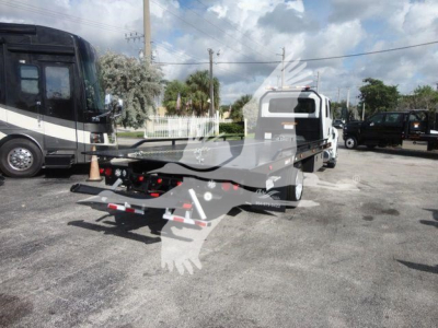 Tow truck flatbed rollback with International MV in background, stock MV607EXCAB22XLP; flatbed view shows hitch and reflective markings.