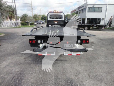 Flatbed rollback truck rear view with hydraulic ramp sections and taillights.