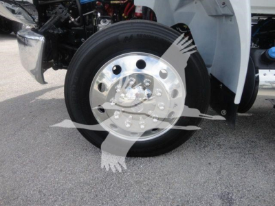 Truck front wheel close-up showing chrome hub and black tire on International MV model cab; wheel bolts and rim visible.