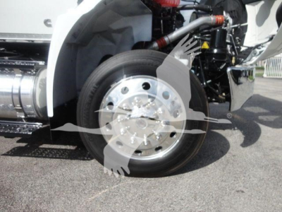 Truck front wheel and suspension view showing polished aluminum wheel, white fender, and hydraulic components.