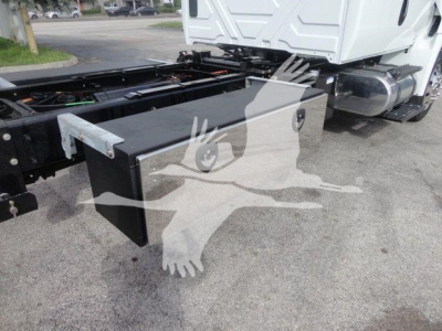 Truck chassis with a large rectangular toolbox mounted behind the cab on a white International MV truck.