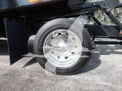 Truck wheel and tire on a rollback tow truck with silver hubcap and black fender visible.