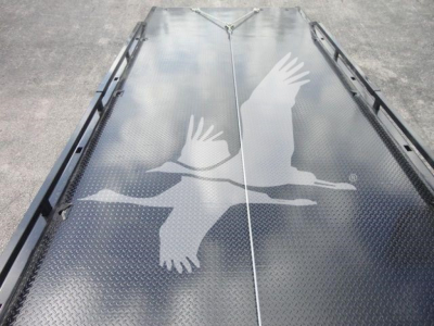 Flatbed trailer or rollback platform with a diamond plate surface featuring a white silhouette of birds in flight.