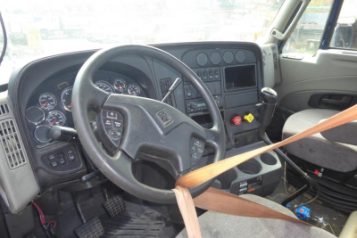 Truck cab interior showing steering wheel, instrument cluster, dashboard with gauges, and gear shifter. Plastic panels and control switches visible.