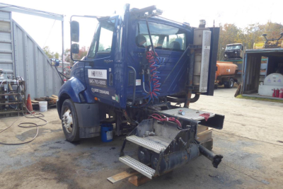 Truck cab rear view of a blue 2012 International PROSTAR+ Daycab showing steps, hydraulic hookups, and fuel/air lines.