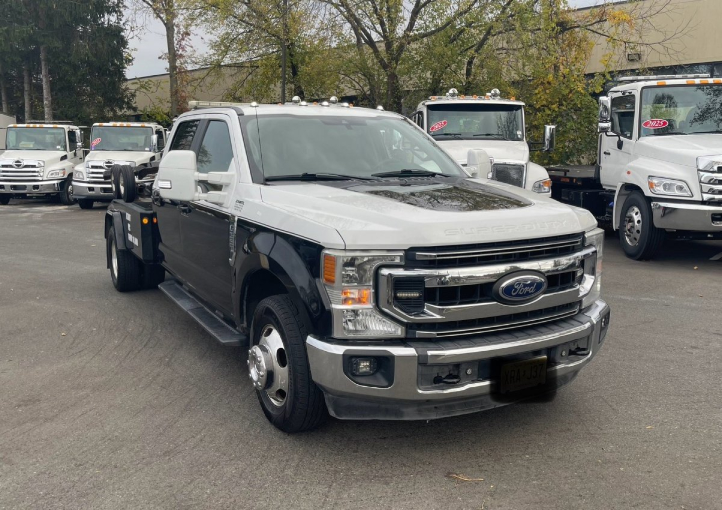 Ford F-350 Super Duty Tow Truck front-left view showing chrome grille, Ford emblem, two-tone white and black cab, flatbed in back.