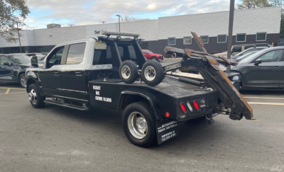 Tow truck 2020 Ford F-350 Super Duty DRW with flatbed and wheel lift, black with chrome accents, in a dealership lot.