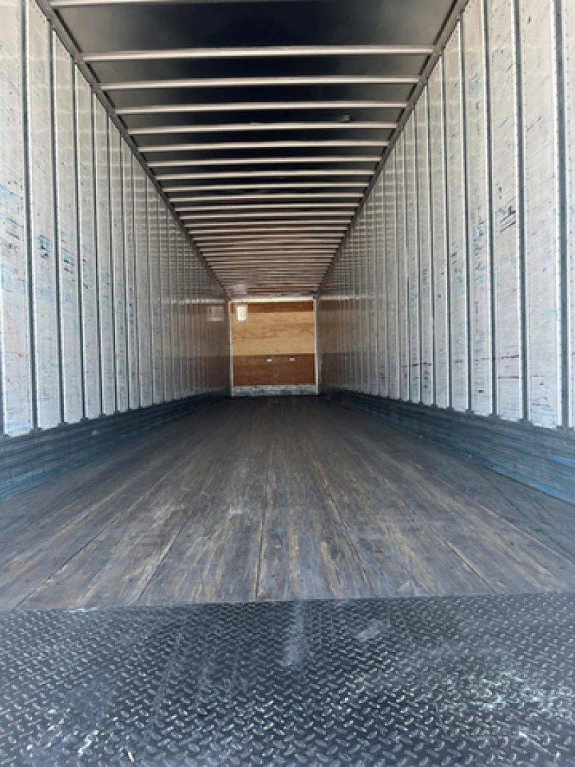 Trailer interior view of a 2014 utility van showing empty cargo space with metal sidewalls and wooden front wall.