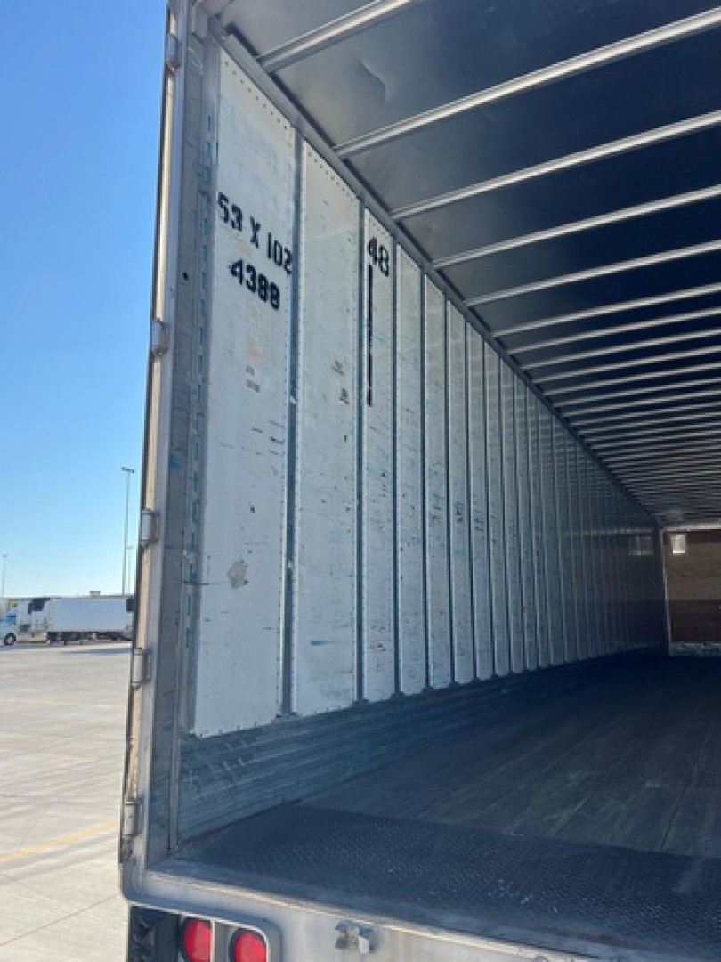 Trailer interior with metal sidewalls and open rear showing empty cargo area.