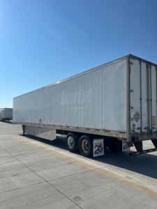 Trailer end of a 2014 utility van semitrailer showing Sparkle or Silver trailer with wheels, side signage, and rear doors in a parking lot.