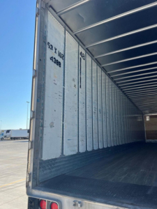 Trailer interior with metal sidewalls and open rear showing empty cargo area.