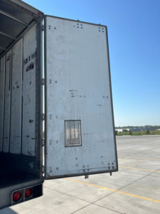Trailer side door of a 2014 utility van showing an interior and open rear with a small vent on the back panel.