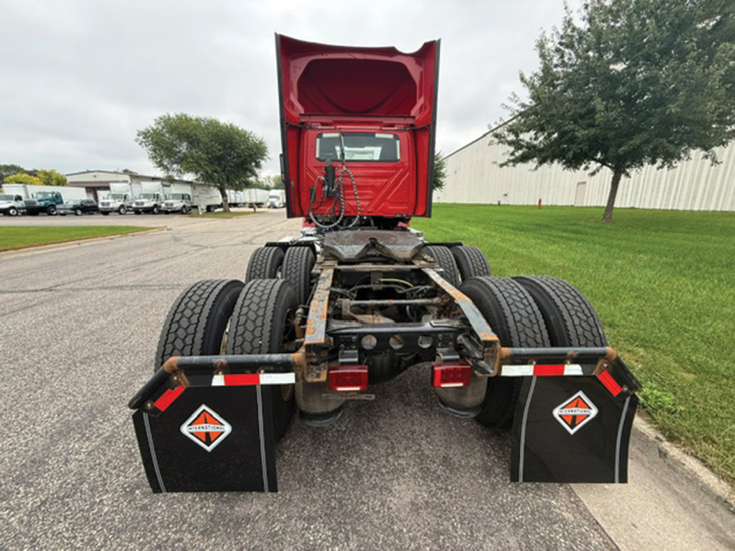 Rear view of a 2019 International LT625 truck tractor cab chassis showing dual rear axles, mud flaps with diamond logo, red fifth wheel housing, and exposed drivetrain.