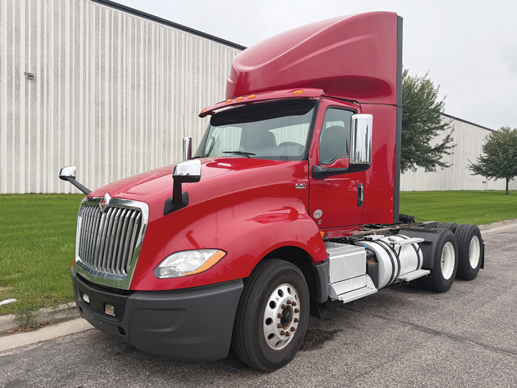 Truck cab and chassis showing red 2019 International LT625 daycab with aluminum fuel tanks and dual rear axles.