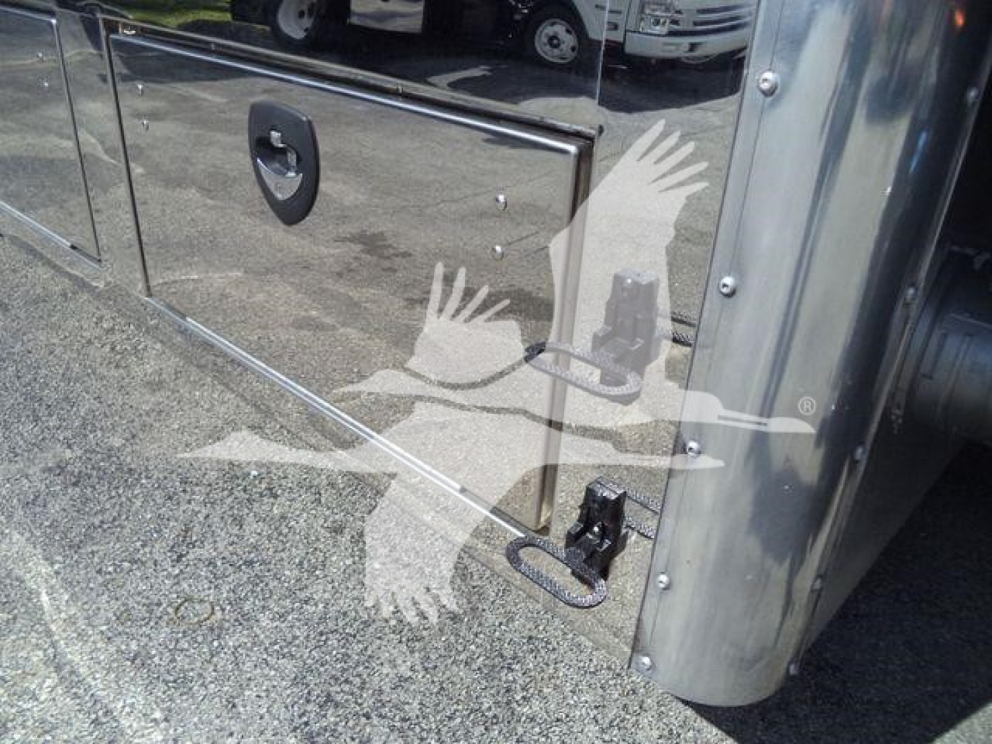 Truck side panel with metal toolbox and latching handle; chrome stainless surface reflecting surroundings.
