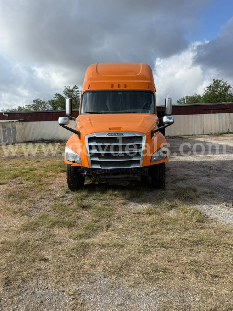 Front view of an orange Freightliner Cascadia truck cab with large grille and chrome mirrors.