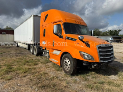 Freightliner Cascadia truck in orange with a white trailer attached, side view showing cab and highway tires.