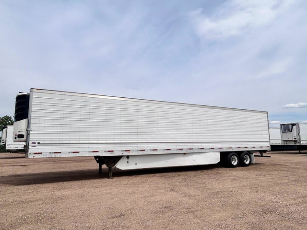 Trailer side view showing refrigerated utility trailer with white exterior and dual rear axles.