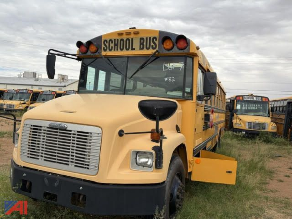 School bus in-service front-left view showing beige body, black bumper, and 'SCHOOL BUS' sign on yellow roof.