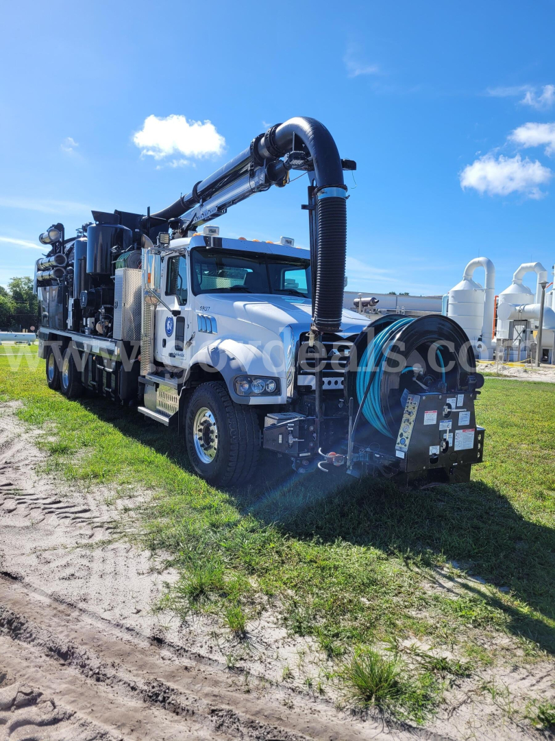 Mack GU713 vacuum truck showing hose reel and pump equipment mounted on bed.