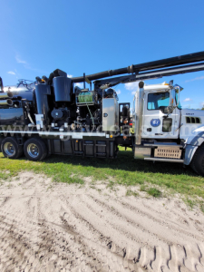 Mack GU713 vacuum truck shown in side view with crane/pump equipment mounted on the chassis.