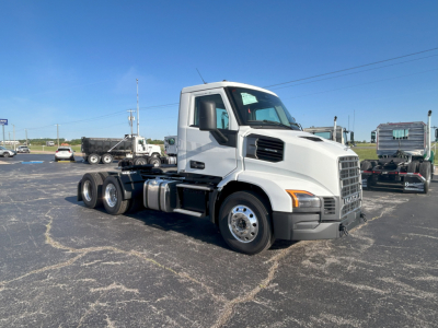 Mack AN64T conventional daycab truck shown in a dealership lot, white cab, 6x4 configuration with visible front grille and side mirrors.