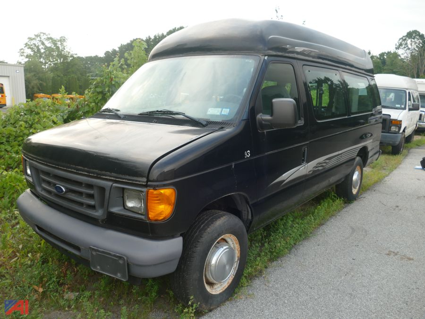 Ford E-250 van with wheelchair lift in a parking lot, black exterior, extended body, front grille and headlights visible.