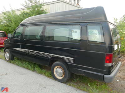 Ford E-250 cargo van with a raised roof and wheelchair lift, black exterior, side windows, rear cargo door, spare wheel on the rear wheel.