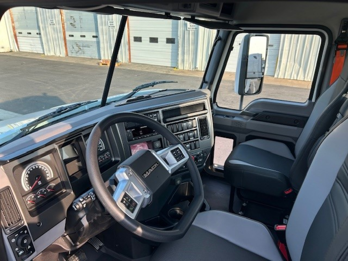 Truck cab interior showing steering wheel, dashboard, and driver seat of a 2025 Mack AN64T conventional daycab.