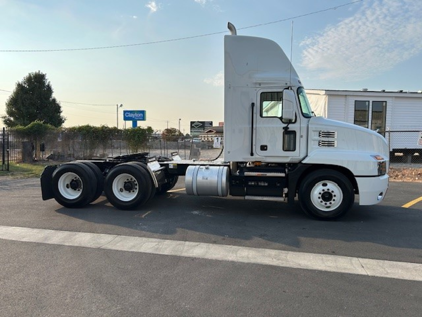Truck cab side profile showing 3-axle configuration and fuel tank on a white Mack AN64T conventional daycab.