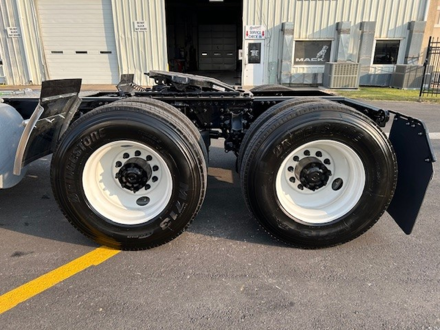 Mack AN64T conventional daycab truck rear dual axle with white wheels and tires, chassis frame visible.